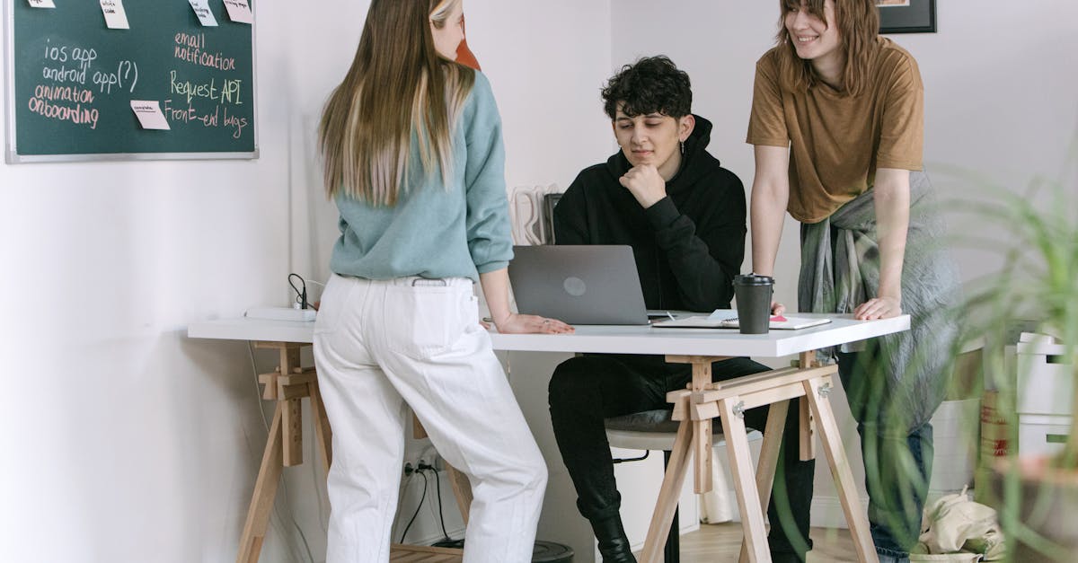 Duas pessoas colaborando ao redor de um laptop com anotações e gráficos